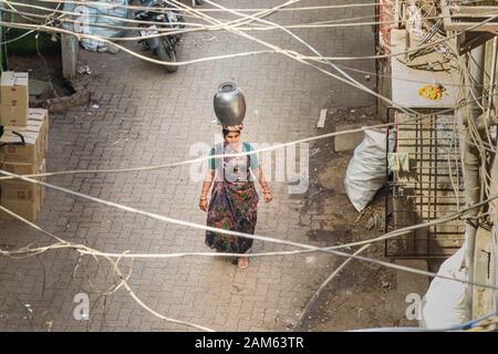 Indianerin mit Topf auf dem Kopf auf der Straße in Dharavi Slum in Mumbai. Indien Stockfoto