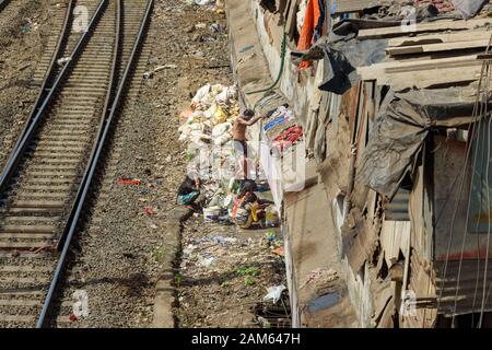 Indische Leute waschen auf der Straße in der Nähe der Suburban-Eisenbahn in Dharavi Slum in Mumbai. Indien Stockfoto