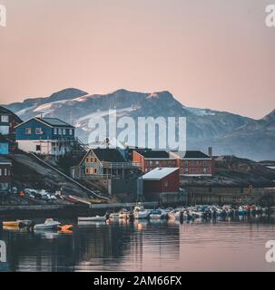 Blick auf den Sonnenuntergang über Maniitsoq arktische Stadt in Grönland. Berge im Hintergrund während der Mitternachtssonne. Farbenfrohe Häuser und Panorama. Ansicht zum Anschluss mit Stockfoto