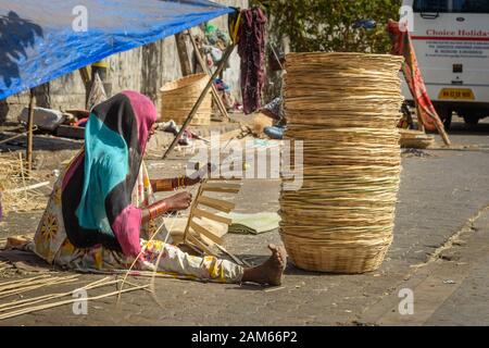 Indische Frau, die auf der Straße in Dharavi Slum in Mumbai einen Korbkorb anstellt. Indien Stockfoto