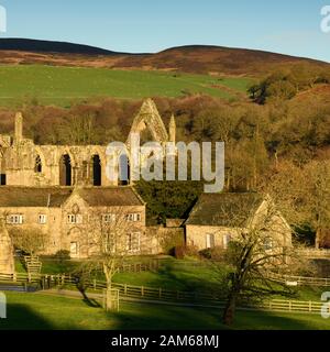 Malerische ländliche Ansicht der alten, malerischen monastischen Priorat Ruinen, historische Old Rectory and sunlit Fells - Bolton Abbey, Yorkshire Dales, England, UK. Stockfoto