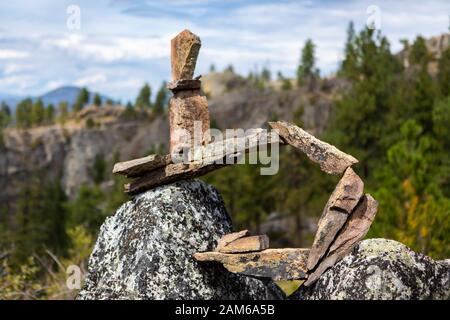 Mittlerer Schuss von Inukshuk in Kanada, British Columbia, Kanada. Inuksuk aus gehäuften Steinen für Kommunikation, Navigation. Waldberge Hintergrund Stockfoto