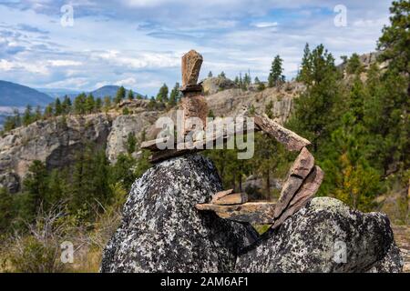 Mittelgroßer Schuss ungewöhnlicher Inukshuk-Steinfigur steht ausgeglichen auf Felsen. Struktur aus Felsen, Okanagan Valley, British Columbia, Kanada Stockfoto