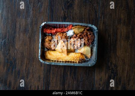 Nehmen Sie indisches Essen Platte mit Huhn Pakora, Aloo Tikki, Samosas Samsa und Frühlingsrollen in Kunststoff Container/Paket. Traditionelle Speisen. Stockfoto