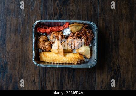 Nehmen Sie indisches Essen Platte mit Huhn Pakora, Aloo Tikki, Samosas Samsa und Frühlingsrollen in Kunststoff Container/Paket. Traditionelle Speisen. Stockfoto