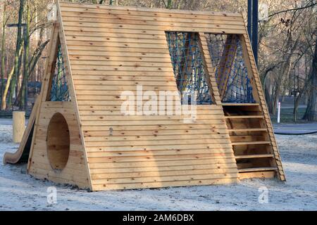 Spielplatz im Park mit Holzschwinge und Kletterrutsche. Moderner Spielplatz für Kinder aus natürlichen Materialien. Stockfoto