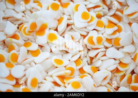 Weiß mit gelbem Mittelgelee und Blick auf den oberen Rand. Kaumarmalade mit Fruchtaroma Hintergrund. Süßigkeiten in Form von Spiegeleiern. Stockfoto