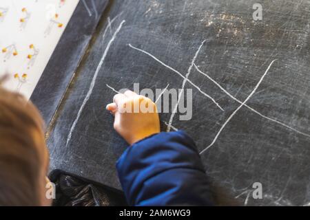 Die Hand eines Kindes zieht mit Kreide auf eine Tafel Stockfoto