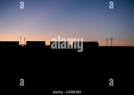 Direct Rail Services 88 bi-Modus für elektrischen und Diesellok Schleppen einer intermodalen Container Zug auf der West Coast Mainline bei Sonnenuntergang. Stockfoto