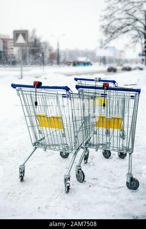 Leerer Warenkorb steht im Winter auf der Straße. Der Marktwagen, der Supermarkt und der Parkplatz. Stockfoto