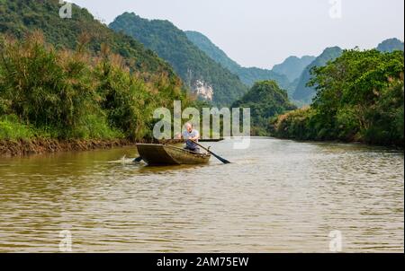 Asiatischer Mann rudert Sampan auf dem Fluss mit Blick auf Kalkkarstberge, Tam Coc, Ninh Binh, Vietnam, Asien Stockfoto