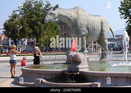 Bergamo, Italien - 05. August 2018: Leute, Foto bei der Statue der Dinosaurier in der Nähe des Hauptbahnhofes. 100-jähriges Jubiläum der Naturwissenschaften Mu Stockfoto