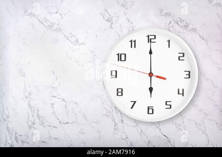 Weiße runde Wanduhr auf weißem Naturmarmor Hintergrund. Sechs Uhr Stockfoto