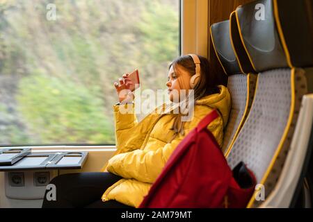 Jugendlicher Mädchen mit Kopfhörer auf dem Kopf in einer S-Bahn sitzen Stockfoto