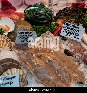 LONDON, Großbritannien - 27. APRIL 2019: Auswahl an frischem Fisch und Meeresfrüchten zum Verkauf an einem Fischhändler-Marktstand mit Preisschildern Stockfoto