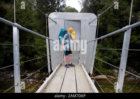 Gehen Sie auf dem Old Ghost Road Trail, Lyell nach Seddonville, Neuseeland. Possum Proof Brückentür auf einer Fußgängerbrücke über den südlichen Zweig des Flusses Mokinhinui Stockfoto