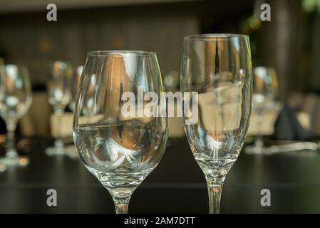 Seitenansicht von zwei verschiedenen leeren Glasbechern auf einem schwarzen Tisch. Stockfoto