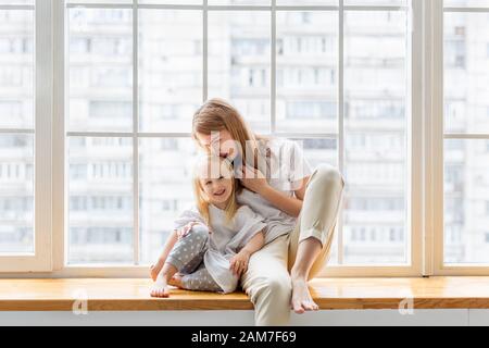 Glückliche Mutter umarmt ihr nettes Mädchen, während Spaß zusammen Stockfoto