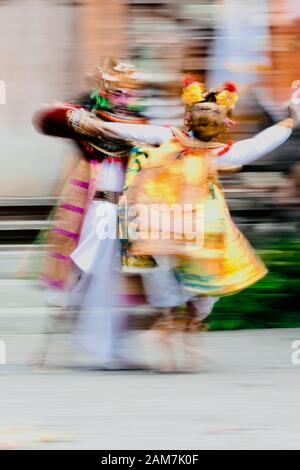 Wirbelnde Bewegung von männlichen und weiblichen hinduistischen Tempeltänzern, die in gelben, goldenen, roten und weißen Kostümen und goldenen Kronen gekleidet sind, die im Tempelhof tanzen. Stockfoto