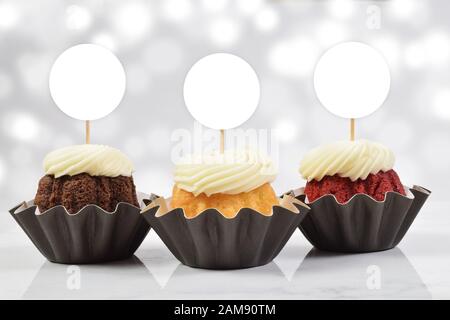 Ein verführerisches Cupcake-Topp mit drei leckeren Gourmet-Cupcakes auf weißem Marmorhintergrund. Fügen Sie Ihren eigenen Entwurf zu den Kupentürenoberhäuschen hinzu. Stockfoto