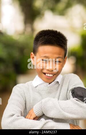 Porträt eines jungen asiatischen Jungen, der draußen lächelt. Stockfoto