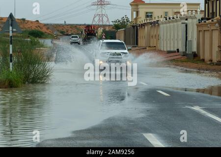 LKW, der auf der Straße durch Hochwasser fährt und in einem Wohngebiet große Wasserspritzer macht. Stockfoto