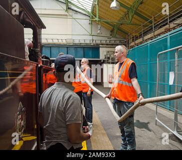 London, Großbritannien - 22. Juni 2019: Eisenbahnarbeiter, die das Wasser in der letzten Dampfmaschine toppen, die auf der District Line zur Ealing Broadway Station fährt Stockfoto