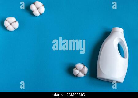 Waschmittel in weißer Kunststoffflasche mit Baumwollkugeln auf blauem Hintergrund, Draufsicht, Kopierraum. Umweltfreundlicher organischer Lebensstil und umweltfreundliches Reinigungskonzept. Stockfoto