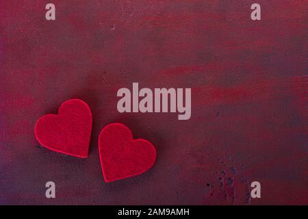 Zwei Herzen auf der in dunkelrot lackierten Holztafel mit Kopierraum für Text. Flaches Lay. Hintergrund für den Valentinstag. Stockfoto