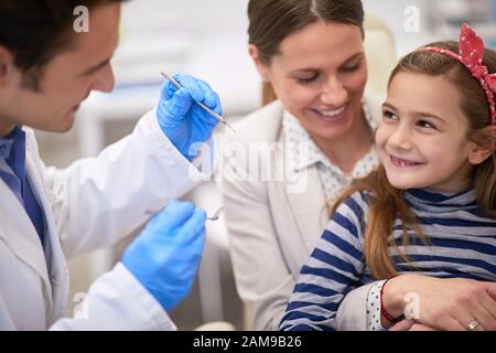 Fürsorgliche Mutter, die ihre Tochter für eine Zahnprüfung, ein Konzept für gesunde Zähne, ermutigt Stockfoto