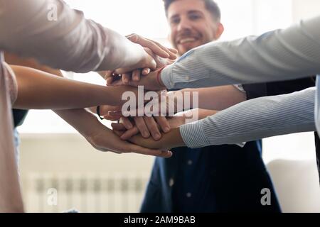 Erfolgreiche Mitarbeiter haben die Hände zusammengestapelt, um erfolgreiche Arbeitsergebnisse im Nahaufnahme zu feiern Stockfoto
