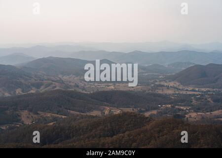 Blick hinunter ins Tal an der kleinen Stadt Kleinen von Byabarra, New South Wales mit Dunstige Berge in der Ferne. Vom Mount Comboyne genommen. Stockfoto