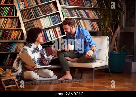 Junge Paare haben Spaß im Zimmer mit Buch und Kaffee Stockfoto