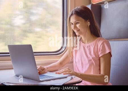 Frau sitzt im Bahnzug, die auf Laptop arbeitet Stockfoto