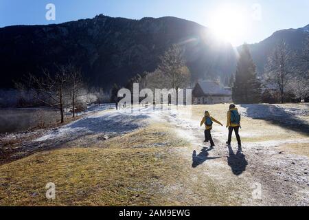 Mutter und Sohn wandern auf einem gefrorenen Weg am Bohinjer See an einem nebligen sonnigen Wintertag, slowenien Stockfoto