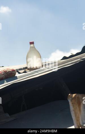 Wellblechdach mit Solar-Klarsichtflasche aus Kunststoff, gefüllt mit Bleichmittel und Wasser, wirkt als natürliche Glühbirne im Gebäude Stockfoto