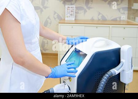 Arzt mit Gerät für ein Laserverfahren in einer Klinik für Kosmetologie. Stockfoto