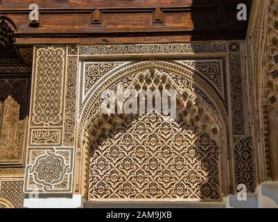 Detail des islamischen Gebäudes. Es handelt sich um eine alte Architektur inmitten der marokkanischen Stadt. Es gibt weiße Wände mit holzgeschnitzten Schriftzeichen. Dort Stockfoto