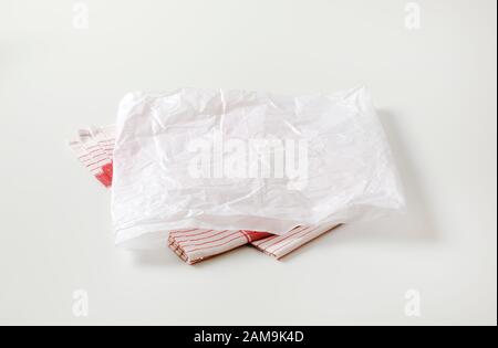 Zerknittertes Blatt weißes Wachspapier (Metzgerpapier) auf dem Teehandtuch Stockfoto