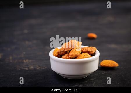 Mandeln auf dunklem Holzhintergrund. Eine Handvoll Nüsse. Stockfoto