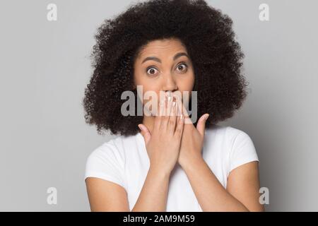 Überraschte eine tausendjährige afrikanische Amerikanerin, die den Mund mit den Händen bedeckt. Stockfoto