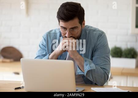 Kopf hat einen nachdenklichen Geschäftsmann in Augenspülung mit Blick auf den Computerbildschirm erschossen. Stockfoto