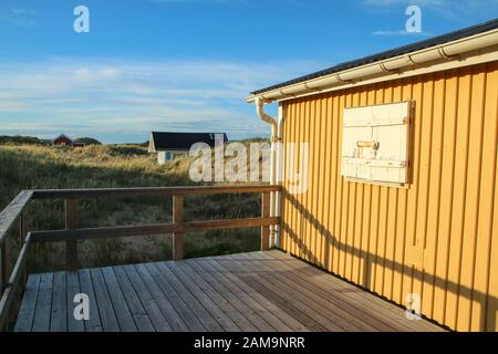 Die traditionellen farbenfrohen Holzhäuschen an der Küste des Meeres in Schweden, versteckt hinter den Dünen. Stockfoto