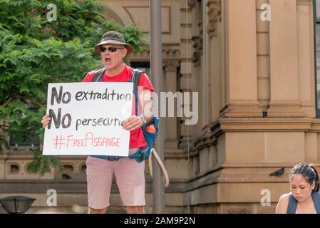 Sydney, Australien 10. Januar 2020: Kurz vor dem massiven Protest gegen den Klimawandel in Sydney steht ein einsamer Protestler an einem niedrigen Steinzaun außerhalb der Sydney Town Hall, um gegen die andauernde Inhaftierung von Julian Assange zu protestieren Stockfoto