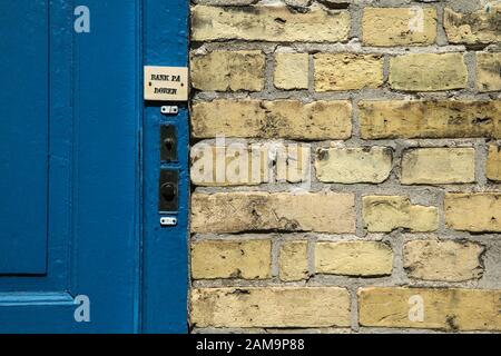 Das Detail eines dänischen Hauses, seiner Tür und seines Eingangs mit einem Teil der Wand. Die Türklingel ist sichtbar. Das Blatt sagt "Door sind geschlossen". Stockfoto