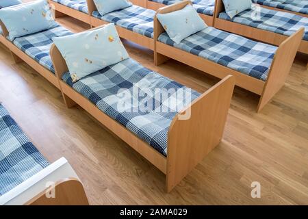 Viele kleine Betten mit frischer Bettwäsche in der Kindertagesstätte Vorschule leere Schlafzimmer Innenraum für komfortable Mittagsschlaf der Kinder. Stockfoto