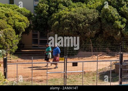 Westkaper, Südafrika, Dezember 2019. Zwei schwarze Frauen, die auf einer Feldstraße arbeiten, haben einen Sicherheitszaun beschmutzt. Stockfoto