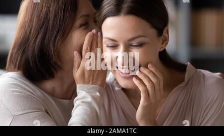 Lächelnde Mutter und Erwachsene Tochter teilen Geheimnisse Stockfoto