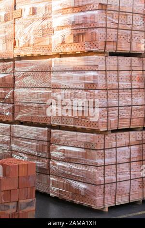 Mehrere Paletten mit Beton Ziegel übereinander im Depot gestapelt. Die industrielle Produktion von Backsteinen. vertikale Foto. Stockfoto
