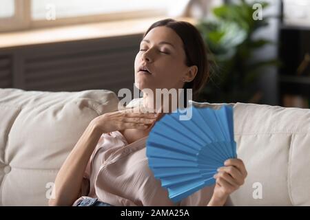 Überhitzte junge Frau fühlt sich mit Handlüfter heiß gewühlt Stockfoto